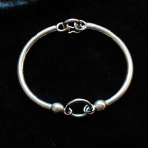 A simple silver bracelet on a black surface