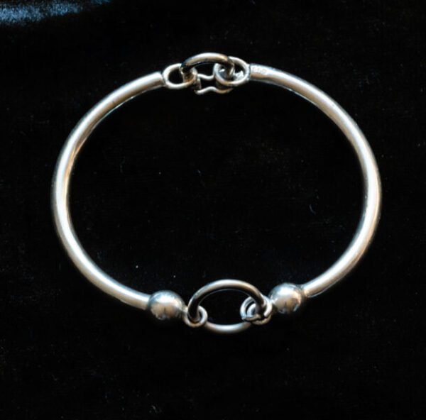 A simple silver bracelet on a black surface